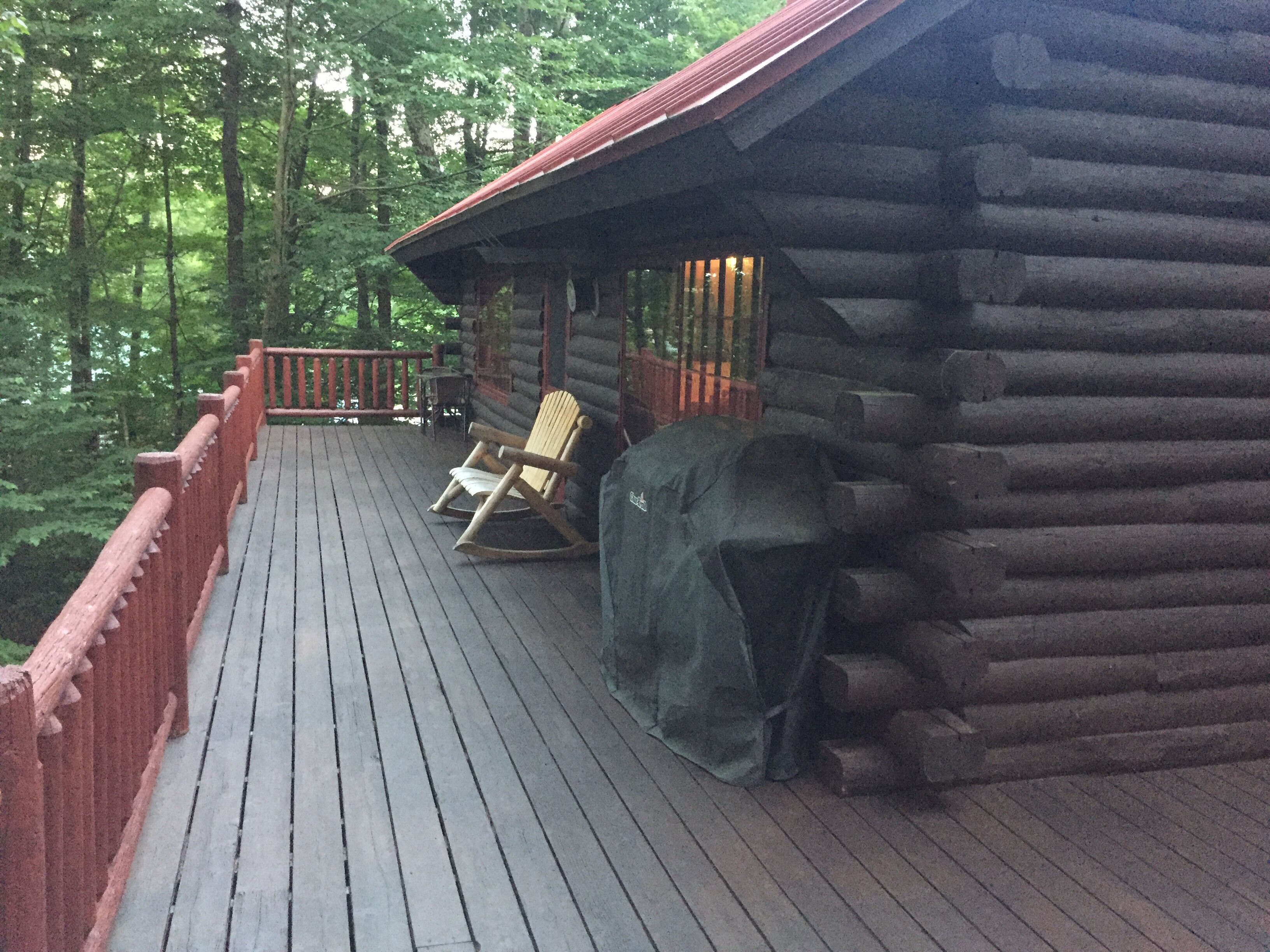 Un patio in legno con una sedia a dondolo e un'area grill coperta.