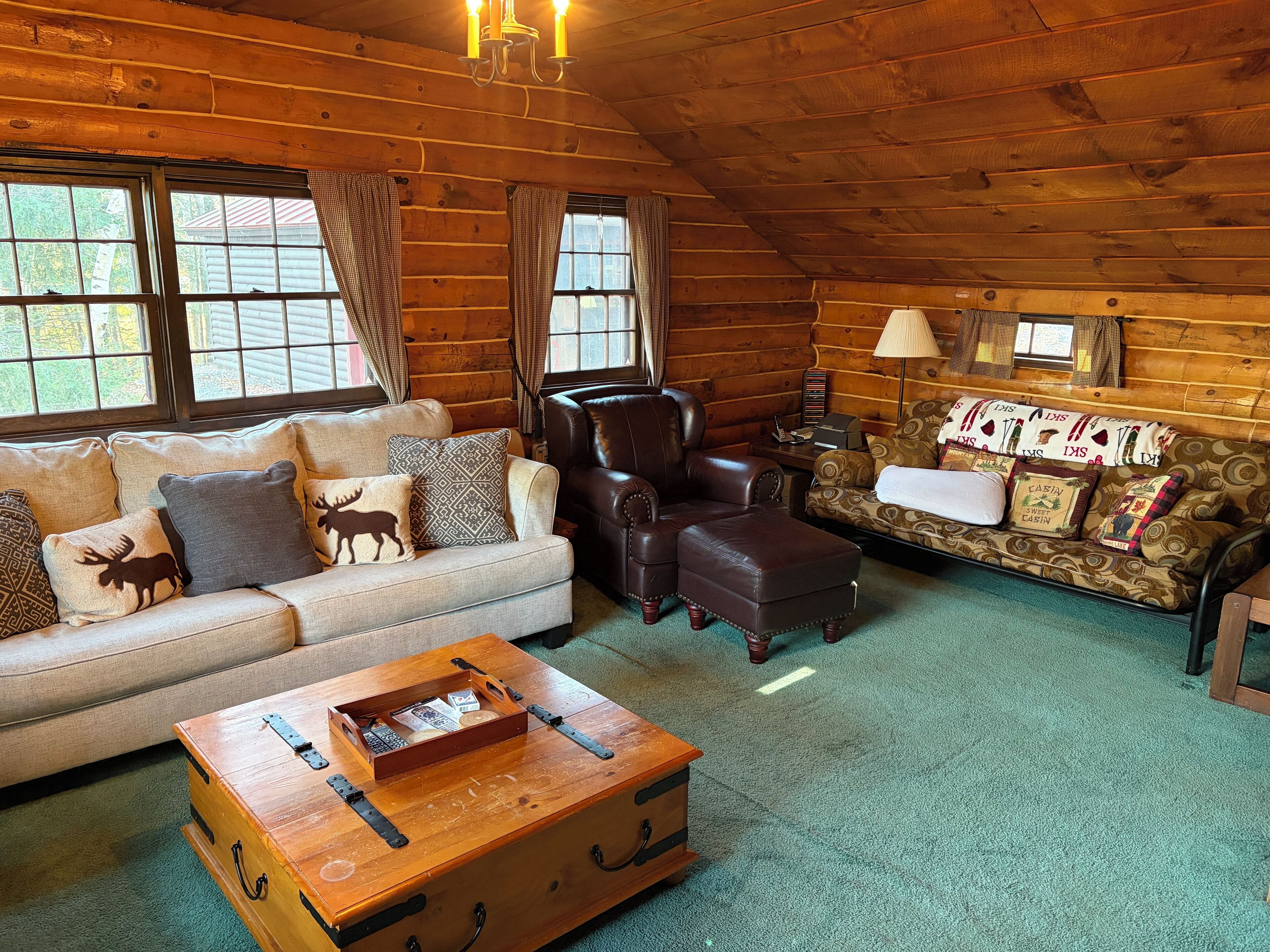 L’intérieur d’un chalet confortable, avec un canapé, un fauteuil, un pouf et un divan à motifs.