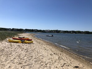 Une plage de sable avec des kayaks et un petit bateau.
