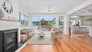 A spacious living room with a fireplace, wicker furniture, and a view of the countryside.