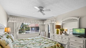 A bedroom with a bed, a dresser, a television, and a ceiling fan. - Sprinkle of Irish charm, beautifully updated, Siesta Dunes 8-205 (Siesta Key)