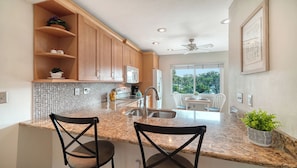 Your spacious kitchen features warm wood cabinetry, granite countertops, and a breakfast bar perfect for casual meals. Natural light streams through the window, creating a bright and welcoming space for cooking and gathering. - Sprinkle of Irish charm, beautifully updated, Siesta Dunes 8-205 (Siesta Key)