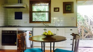 A kitchen with white cabinets, a stove, a sink, and a window overlooking greenery.