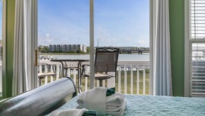 Une chambre d’hôtel avec un balcon donnant sur un plan d’eau et des bâtiments.