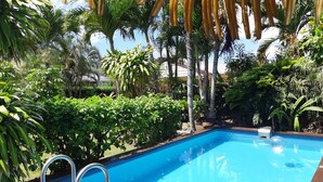 A swimming pool surrounded by lush greenery and palm trees. - Island Time Villas - Villa Kakaia (Muri Beach)