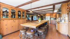 A kitchen with wooden cabinets, a large island with stools, and hanging pendant lights. - Private Pickleball Ct - Indoor Hot Tub - Spa Room - Lift Tkts  (Windham)