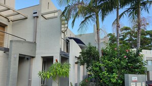 A modern building with a flat roof, a small garden area with plants and a palm tree, and a utility box with multiple outlets. - Seahorse - Avellino filtered  Sea views- Long Beach (Long Beach)