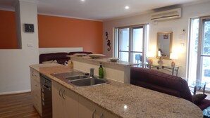 A kitchen with granite countertops, a sink, and a dining area with a red couch. - Seahorse - Avellino filtered  Sea views- Long Beach (Long Beach)