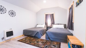 Un dormitorio con dos camas, un radiador, una alfombra y un banco de madera.