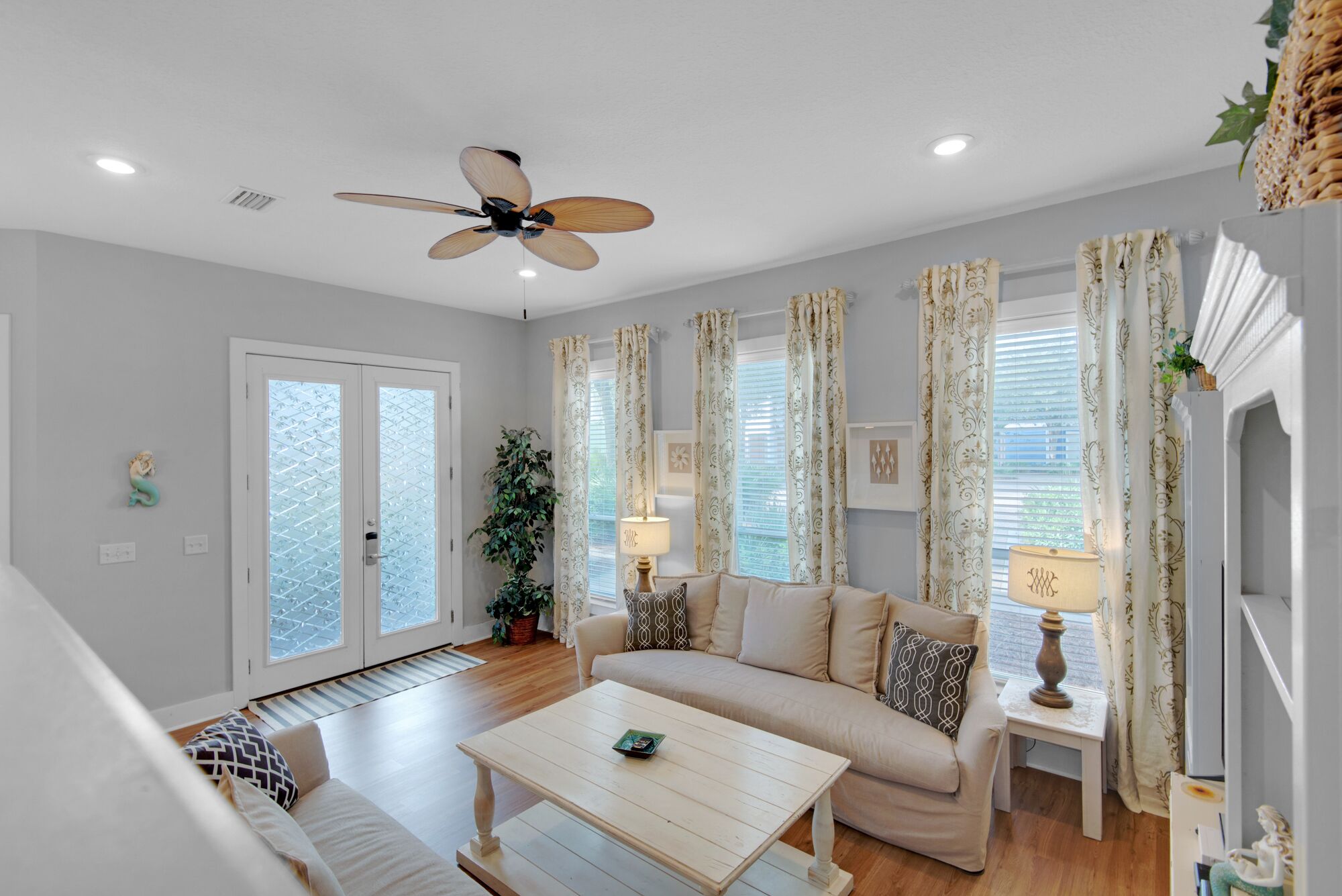 A living room with a ceiling fan, a sofa, a coffee table, and a lamp.