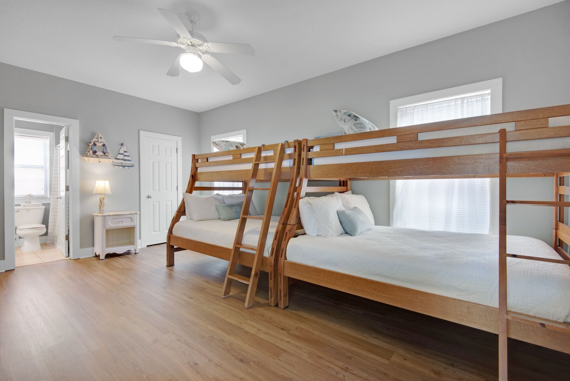 Una cama litera con escalera, un ventilador de techo y una ventana con persianas.