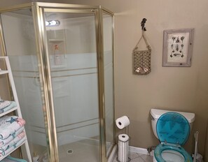 A bathroom with a glass shower enclosure, a toilet with a blue seat, and a framed picture on the wall. - ✻Beautiful & Spacious Oside Oasis Family Retreat✻ (Oceanside)
