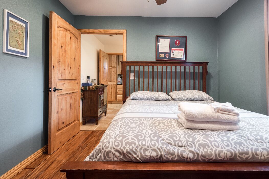 Un dormitorio con dos camas, un armario de madera, un certificado enmarcado en la pared y una puerta que da a otra habitación.