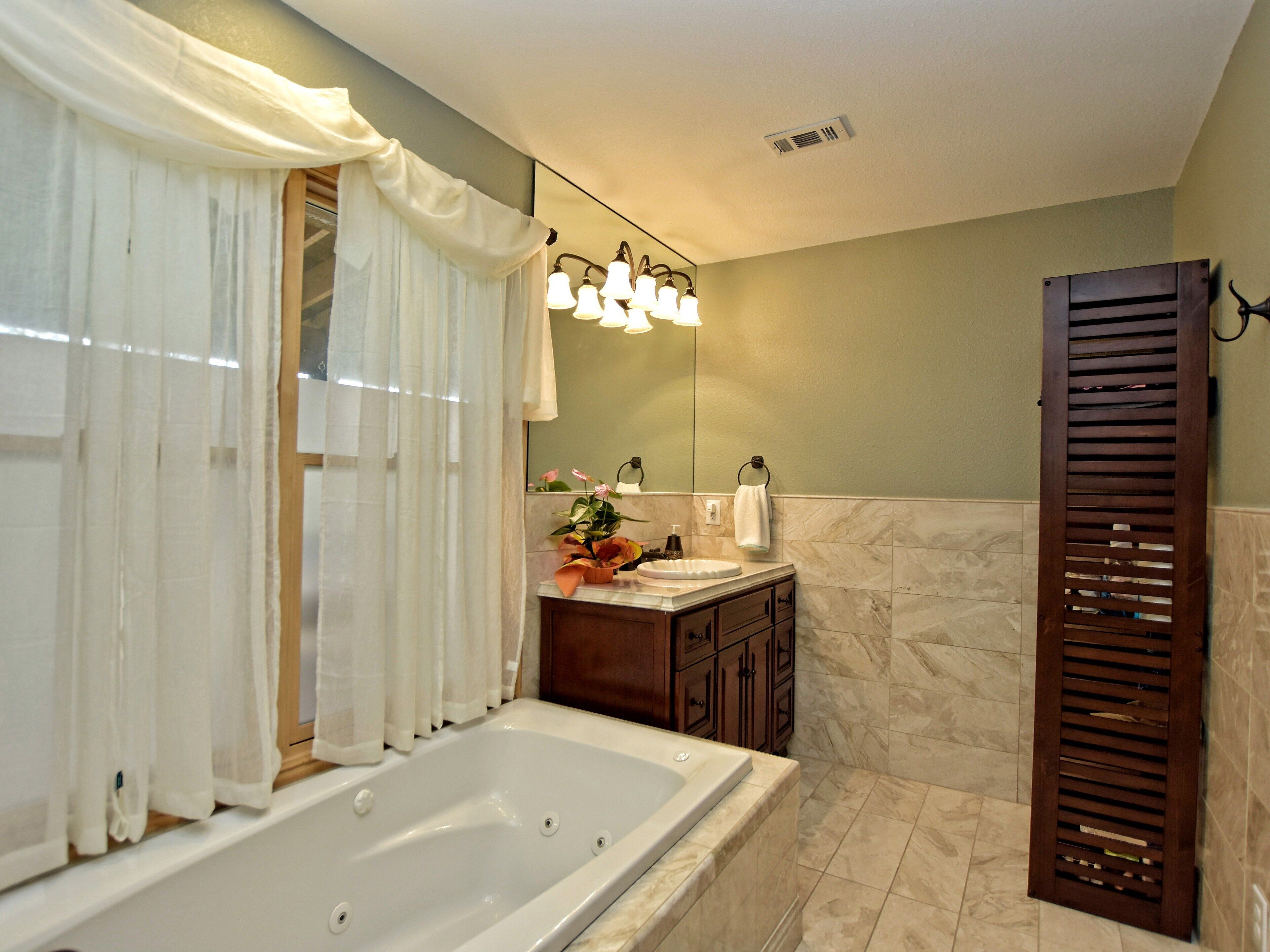 A bathroom with a bathtub, vanity, mirror, and a towel rack.