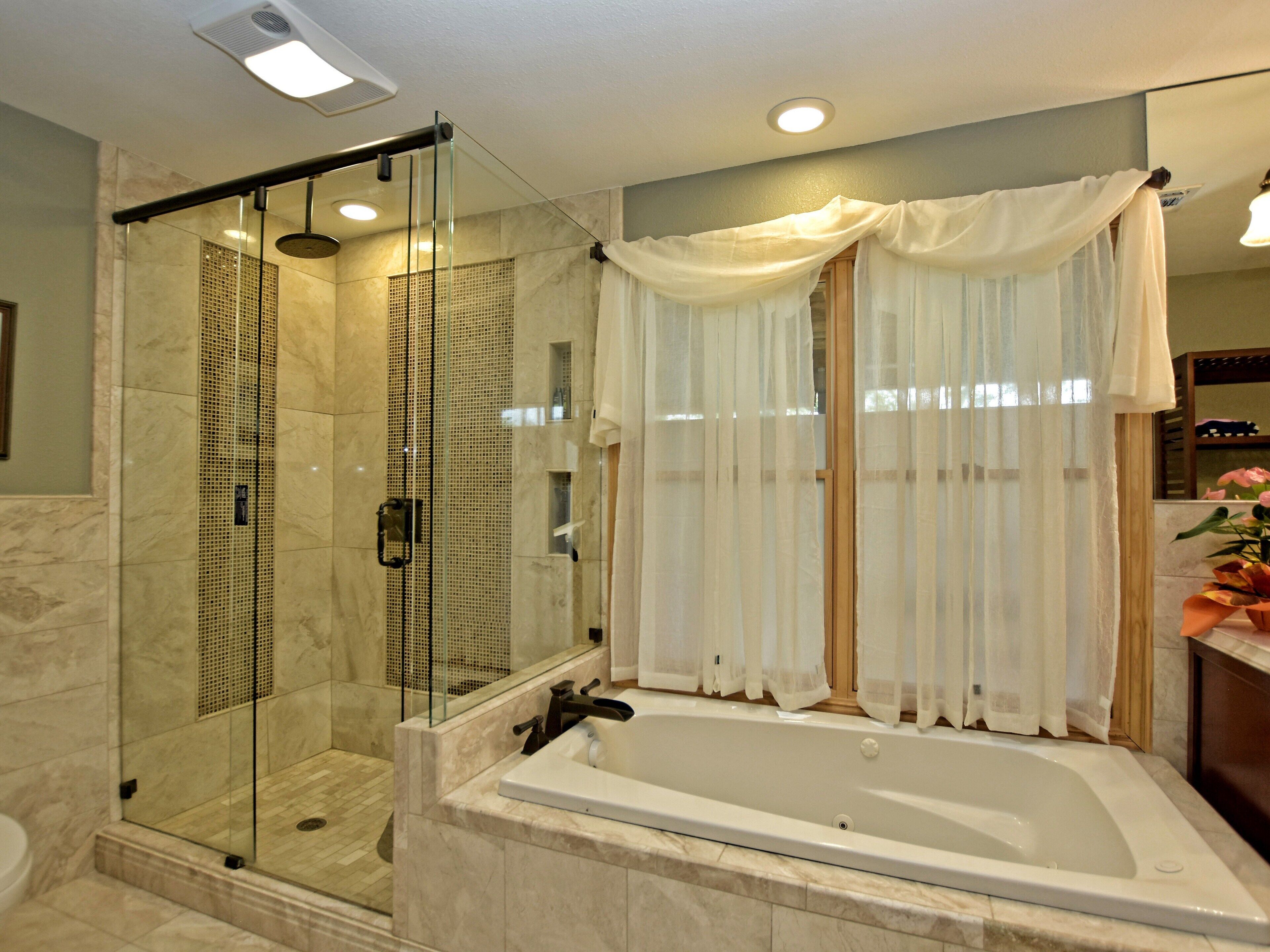 Un bagno moderno con doccia vetrata, una vasca freestanding e un mobile vanitario con specchio.