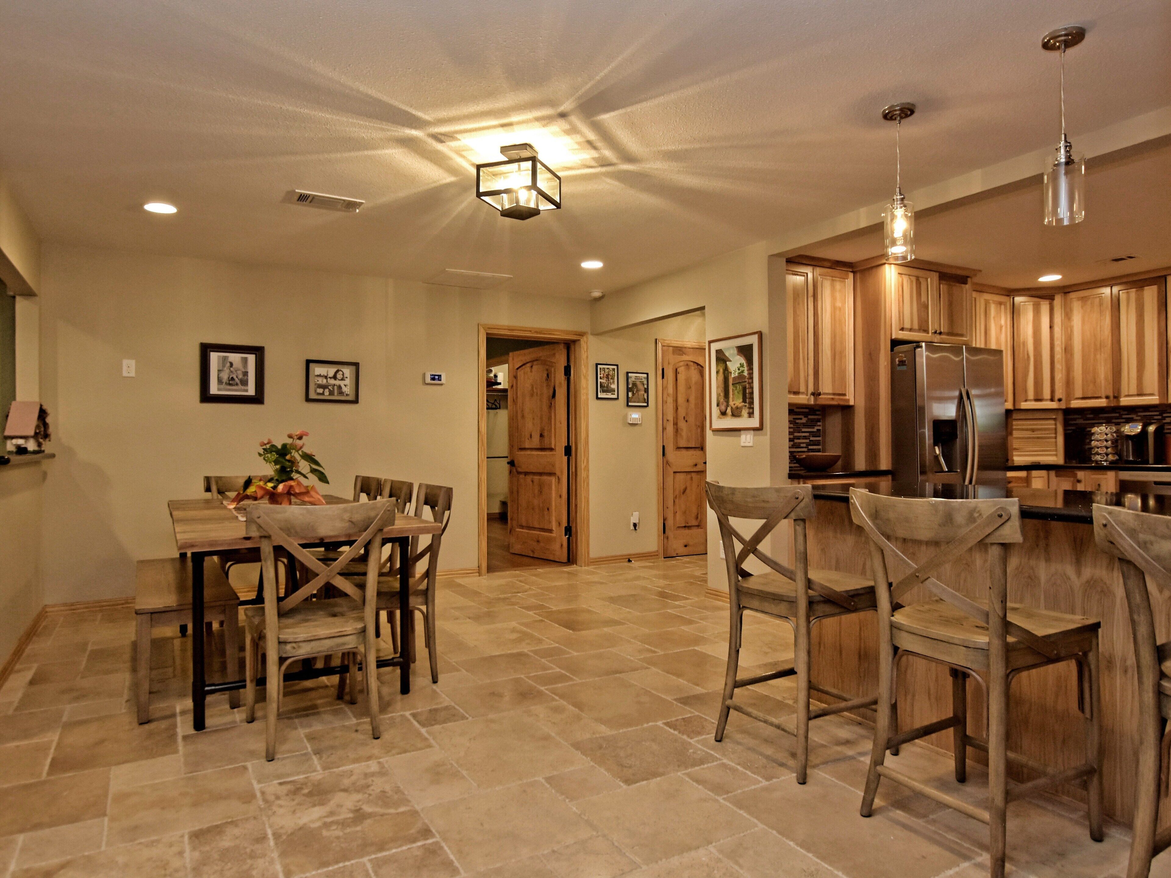 A spacious kitchen with wooden cabinets, a stainless steel refrigerator, and a dining area with a wooden table and chairs.