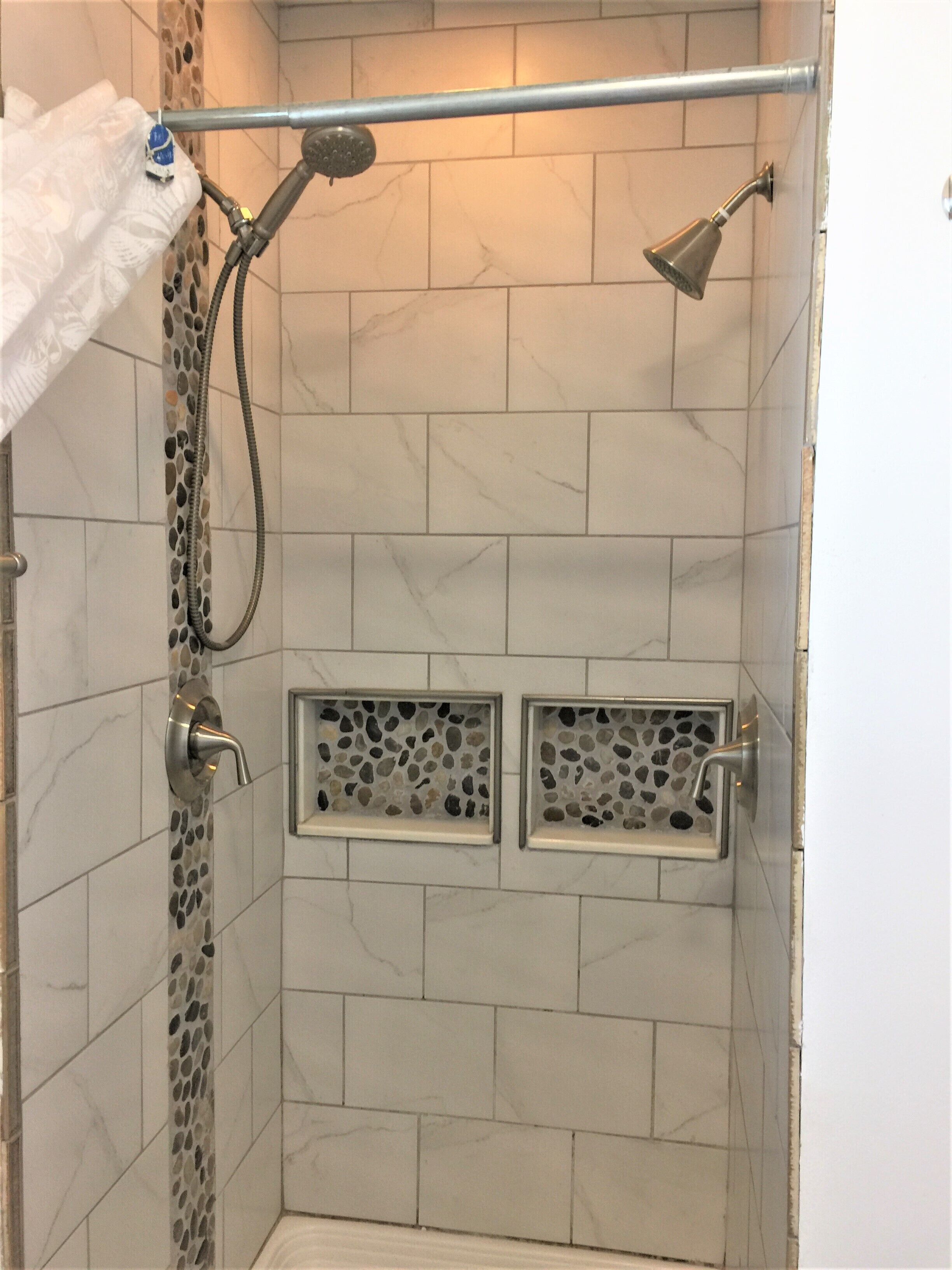Une douche équipée d’un pommeau de douche à main, d’un pommeau de douche fixé au mur et d’un porte-serviettes.