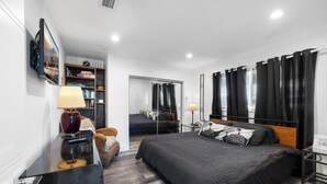 A modern bedroom with a large bed, a desk with a lamp, a bookshelf, and a mirror. - UNIT # 7 Ocean and Downtown view LAUDERDALE BY THE SEA  200+- steps to beach fun (Lauderdale-by-the-Sea)