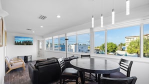 A modern room with a large window, a round table, and a sofa. - UNIT # 7 Ocean and Downtown view LAUDERDALE BY THE SEA  200+- steps to beach fun (Lauderdale-by-the-Sea)