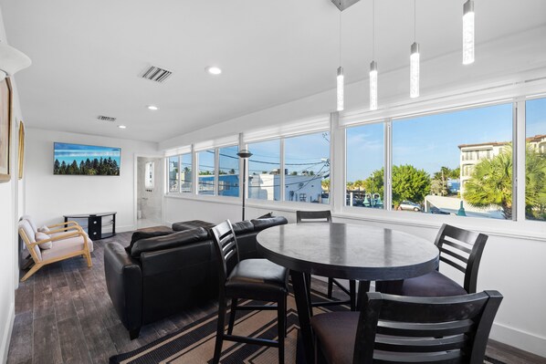 A modern room with a large window, a round table, and a sofa. - UNIT # 7 Ocean and Downtown view LAUDERDALE BY THE SEA 200+- steps to beach fun (Lauderdale-by-the-Sea)