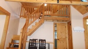 A wooden staircase leading to an upper level with a dining area below.