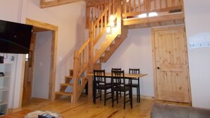 A wooden staircase with a dining area below, a television, and a door.
