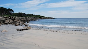 A beach with a rocky shoreline, calm water, and a clear sky. - Maine Dream Cottage (Biddeford)