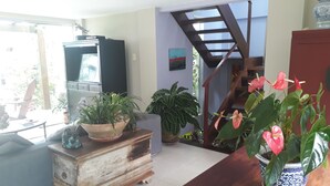 A living room with a wooden cabinet, a television, and various potted plants. - Tranquility on the right side of Ferradura (Buzios)