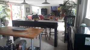 A spacious kitchen with a dining area, featuring a large table, chairs, and a refrigerator. - Tranquility on the right side of Ferradura (Buzios)