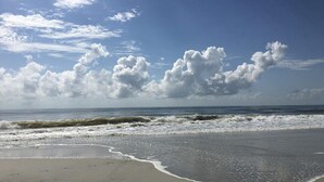 Een strand met golven en een heldere lucht.
