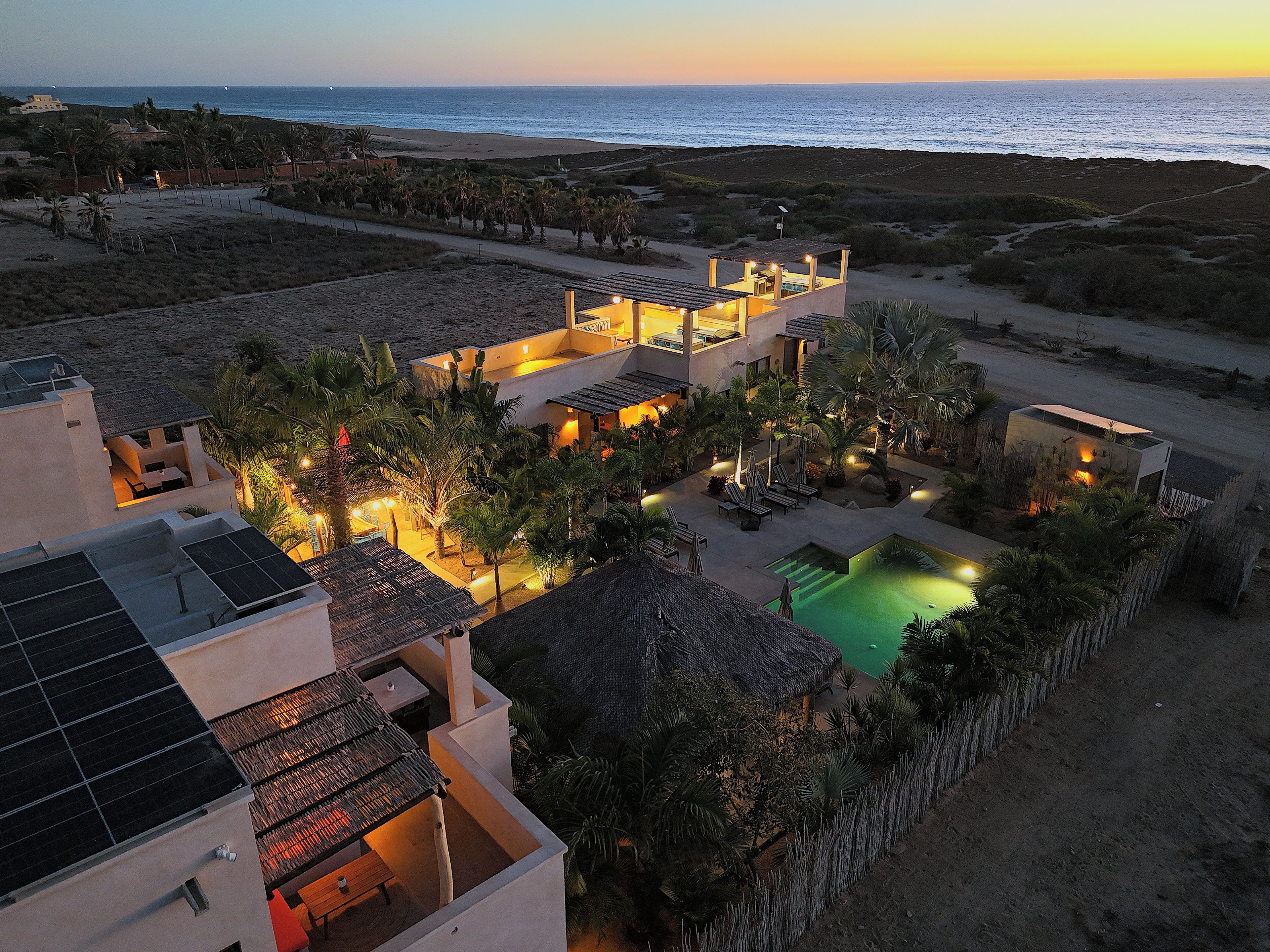 A resort with multiple buildings, a swimming pool, and a view of the ocean.