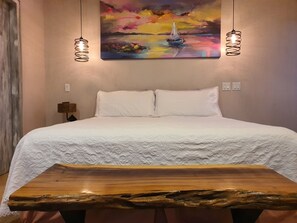 A bedroom with a bed, white pillows, a wooden nightstand, a painting of a sailboat, and two hanging lamps. - Vista Tortuga Ocean View VILLA-AZUL Heated Pool by the BEACH (Todos Santos)