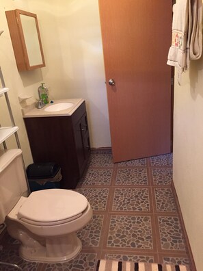 Un baño con inodoro, lavamanos y espejo.