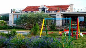 A residential building with a balcony, a swing set, and a garden with lavender.