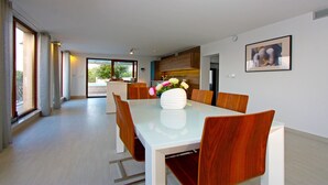 A modern dining area with a glass table, wooden chairs, and a vase of flowers.