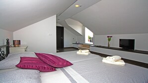 A modern bedroom with a bed, pillows, a bedside table, a lamp, a TV, and a window with a view.