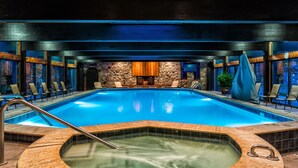 A large indoor swimming pool with a hot tub, lounge chairs, and a stone wall with a fireplace. - Renovated! Cute, 1 bdrm sleeps 2 Golf/ ski. pool and Wifi! new KING bed. (Mancelona)