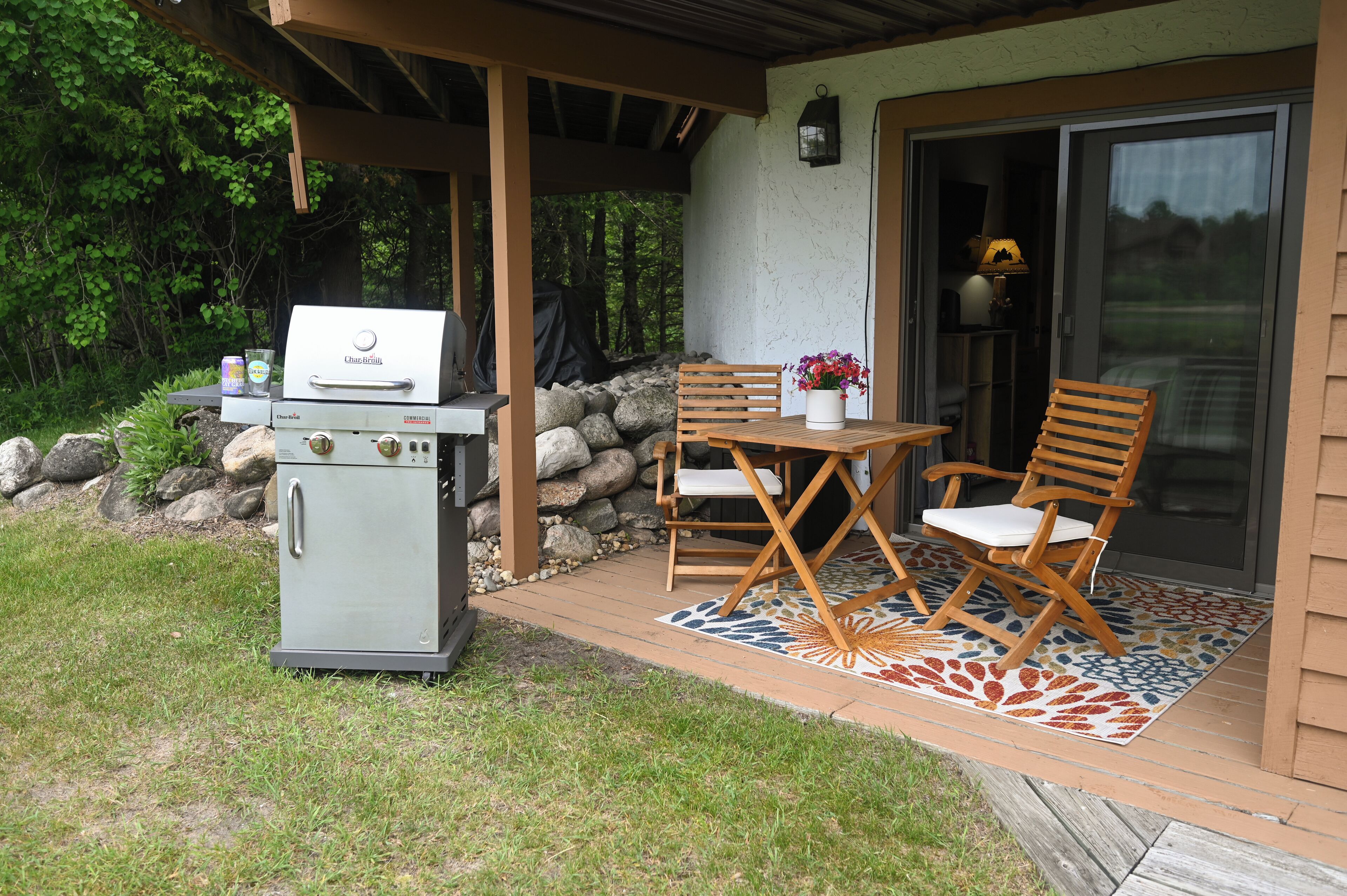 A patio area with a barbecue grill, a table with chairs, and a potted plant.