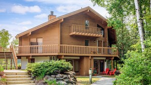 A wooden cabin with a balcony, a stone pathway, and red chairs outside. - Renovated! Cute, 1 bdrm sleeps 2 Golf/ ski. pool and Wifi! new KING bed. (Mancelona)