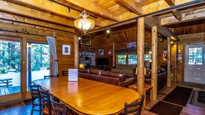 A wooden interior with a large dining table, leather seating, and a fireplace.