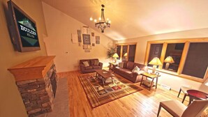 A cozy living room with a stone fireplace, wooden flooring, and a comfortable sofa set.