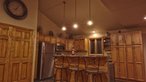 A kitchen with wooden cabinets, a stainless steel refrigerator, a microwave, and pendant lights.