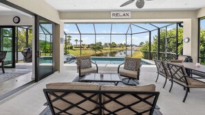 Zona de piscina con ventilador de techo, mobiliario exterior y vistas a una piscina y paisaje.