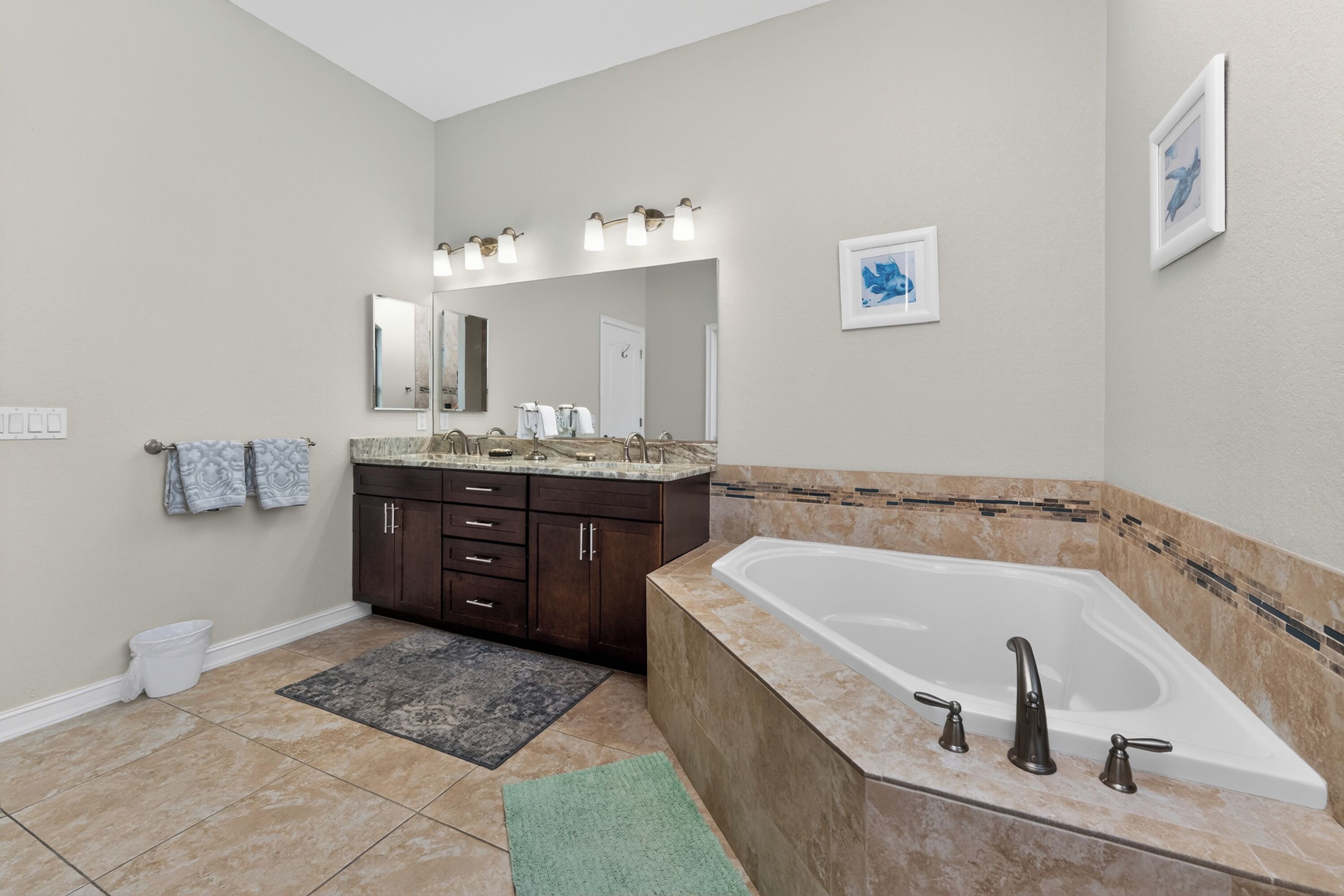 Une salle de bain moderne avec une grande baignoire, un meuble-lavabo avec un miroir et un sol carrelé.