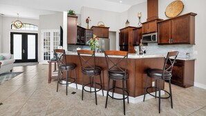 Una cocina moderna con una isla central, taburetes de bar y armarios de madera.