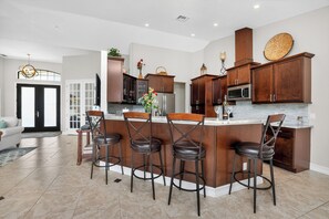 A modern kitchen with a central island, bar stools, and wooden cabinetry.