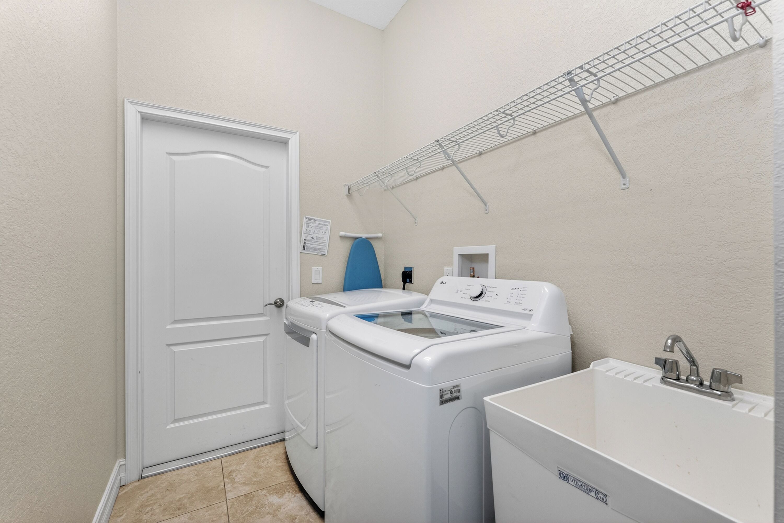 A laundry room with a washing machine, dryer, and sink.
