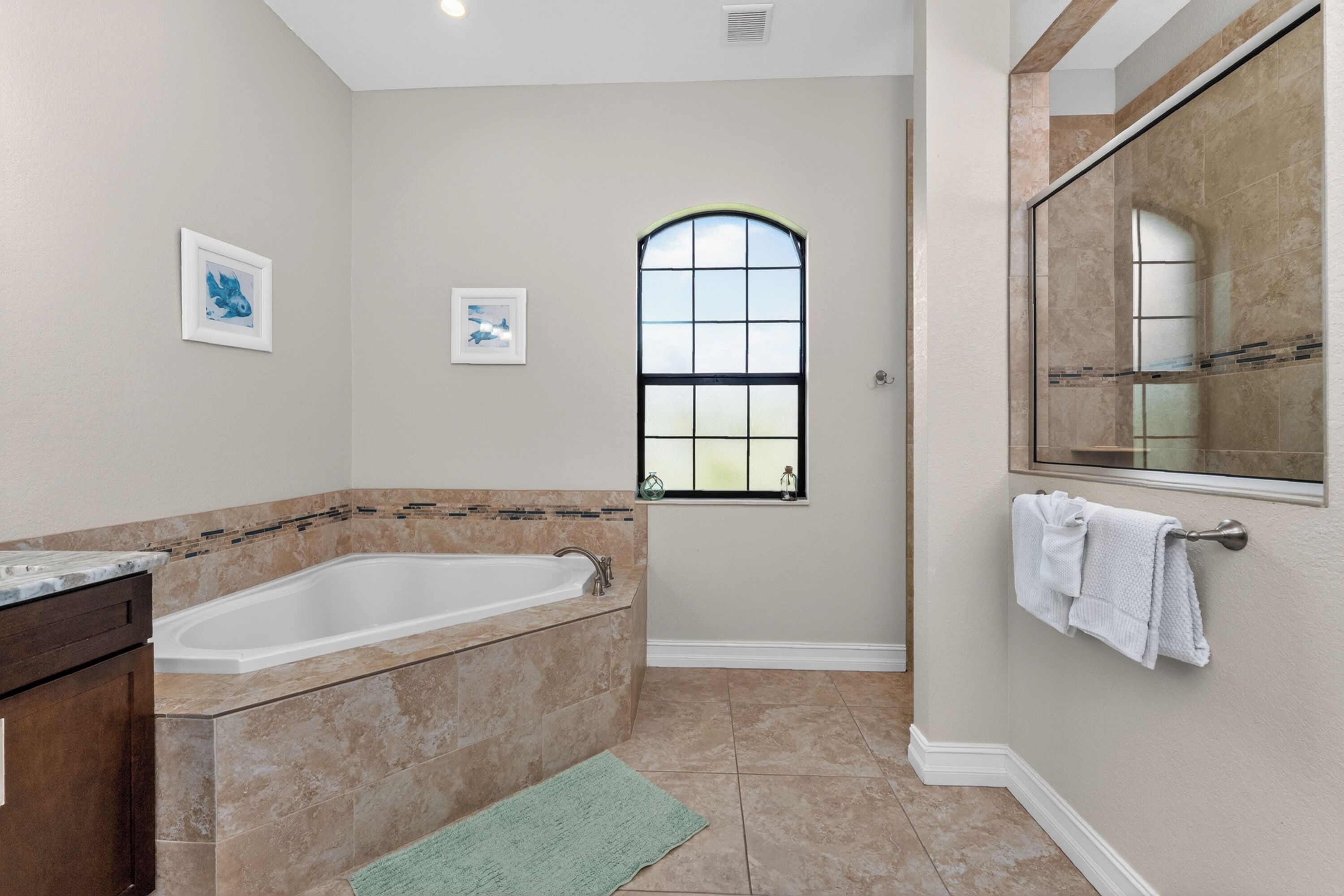 A bathroom with a bathtub, a window, and a mirror.