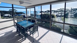Ein geräumiges Zimmer mit großem Tisch und Stühlen, große Fenster mit Blick auf das Meer und die umliegenden Gebäude.