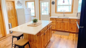 Une cuisine moderne avec des meubles en bois, un îlot central et un réfrigérateur.